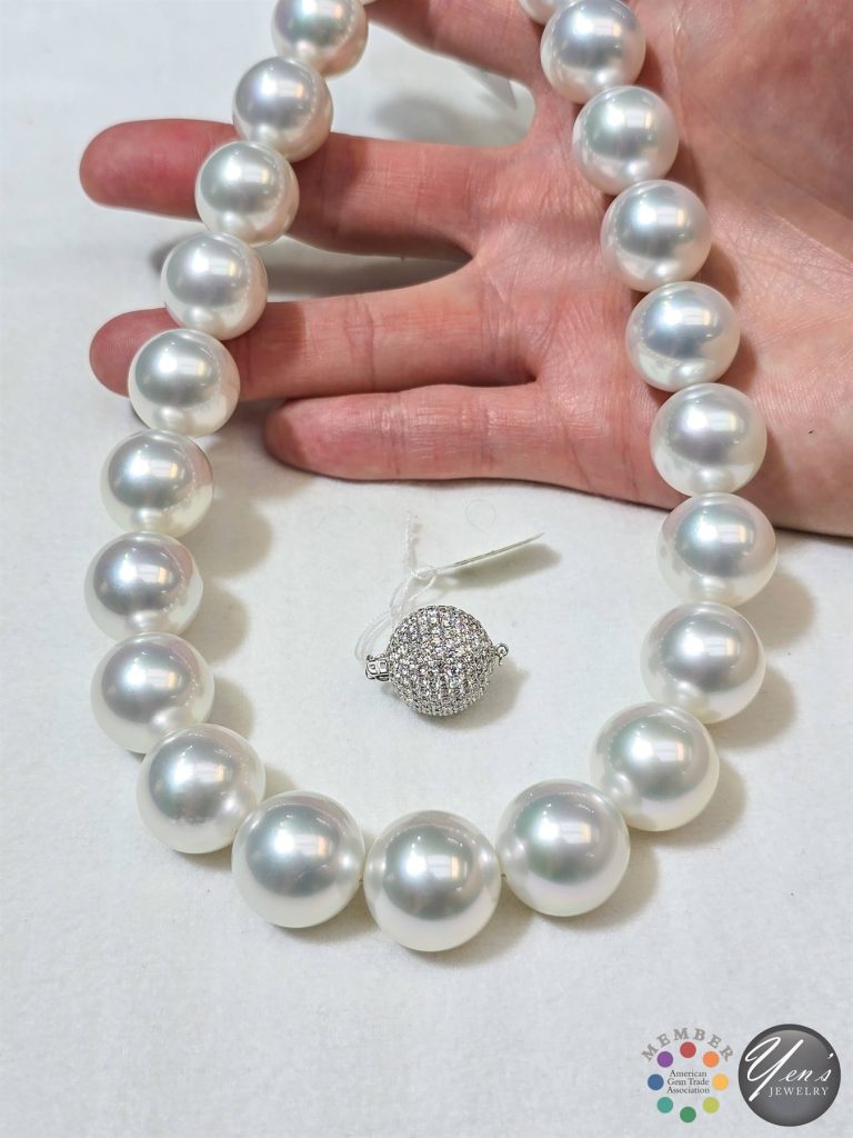 The strand with its 5.9 ct pave diamond ball clasp, held in a hand