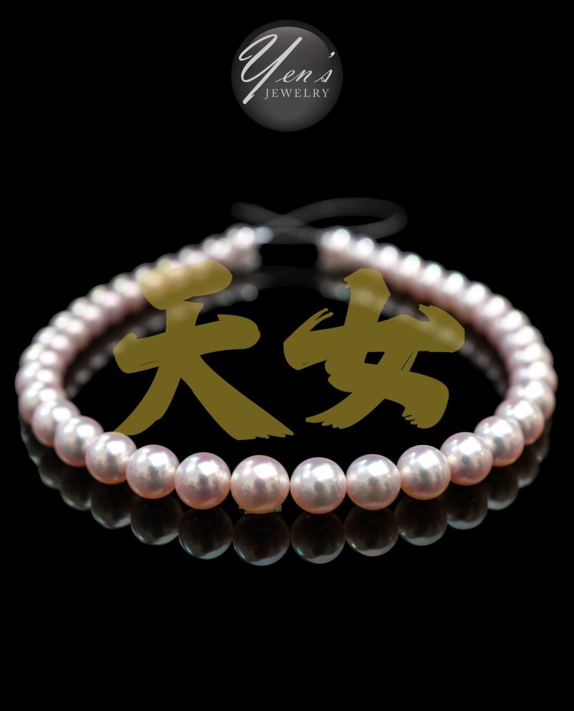 A strand of 10.5 to 11.3 mm Aurora Tennyo Akoya pearls on black, with the characters 天女 (Tennyo) in gold