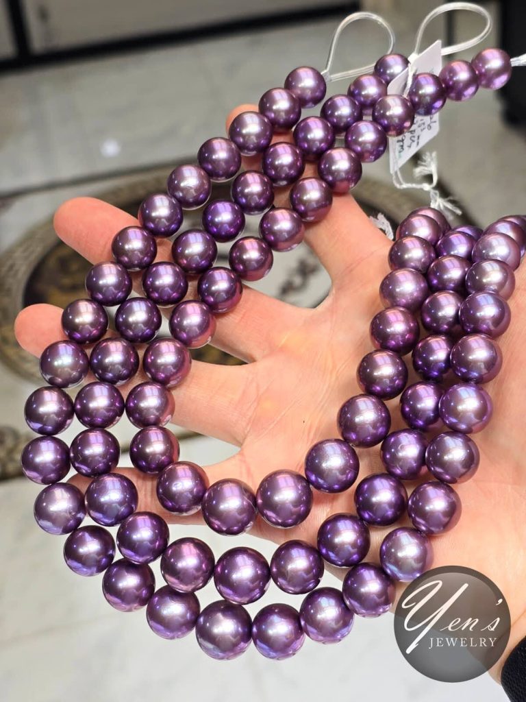 Three Amethyst Purple Edison pearl strands held in a hand to show size