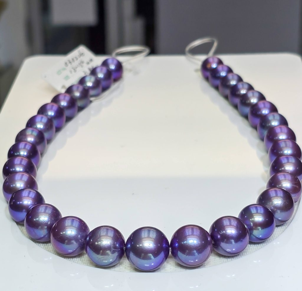 Tanzanite Blue Edison pearl strand with blue-violet metallic overtone, on a white tray